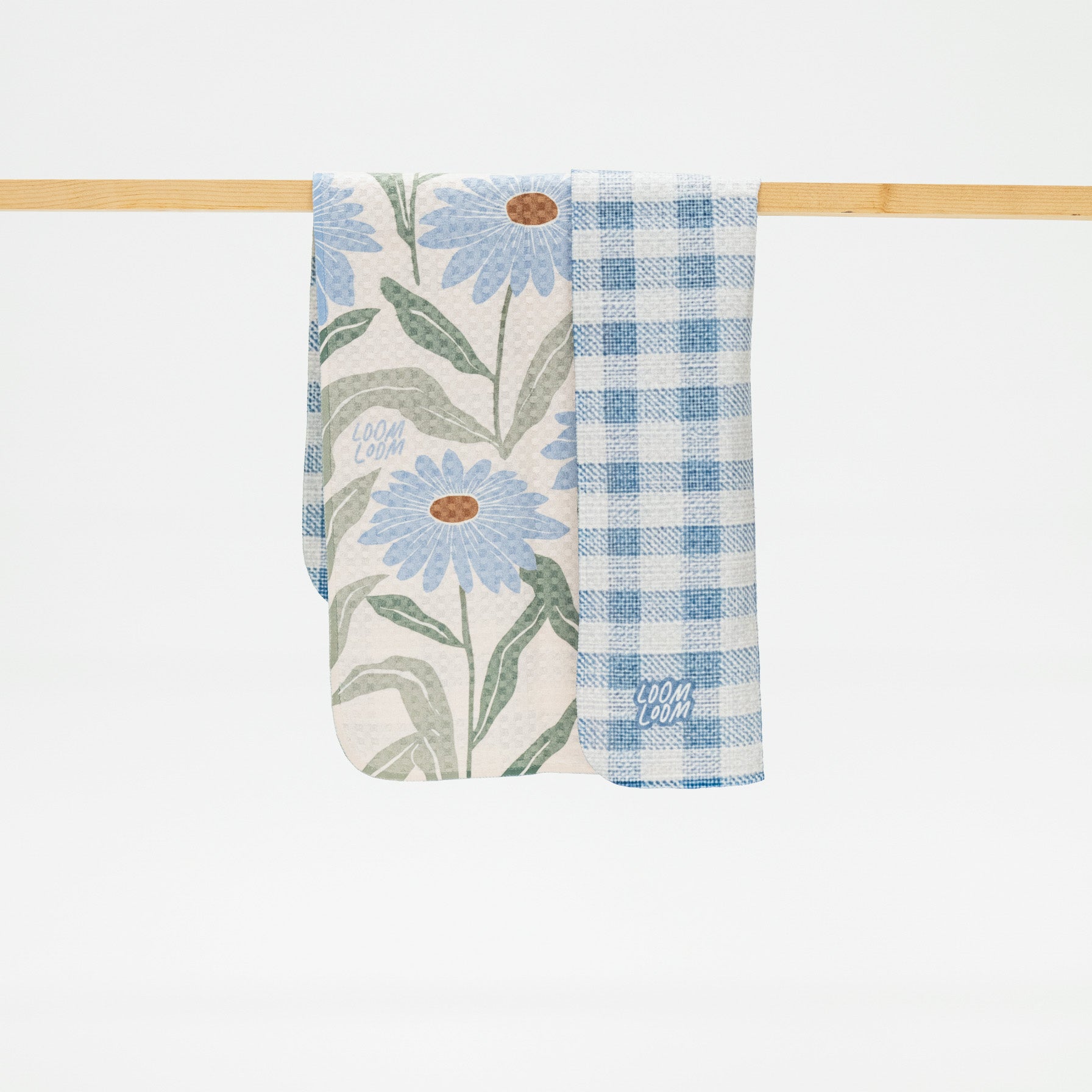 reversible kitchen towel with floral and checkered patterns hanging on a wooden rod.