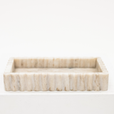 A beige marble tray with fluted sides.