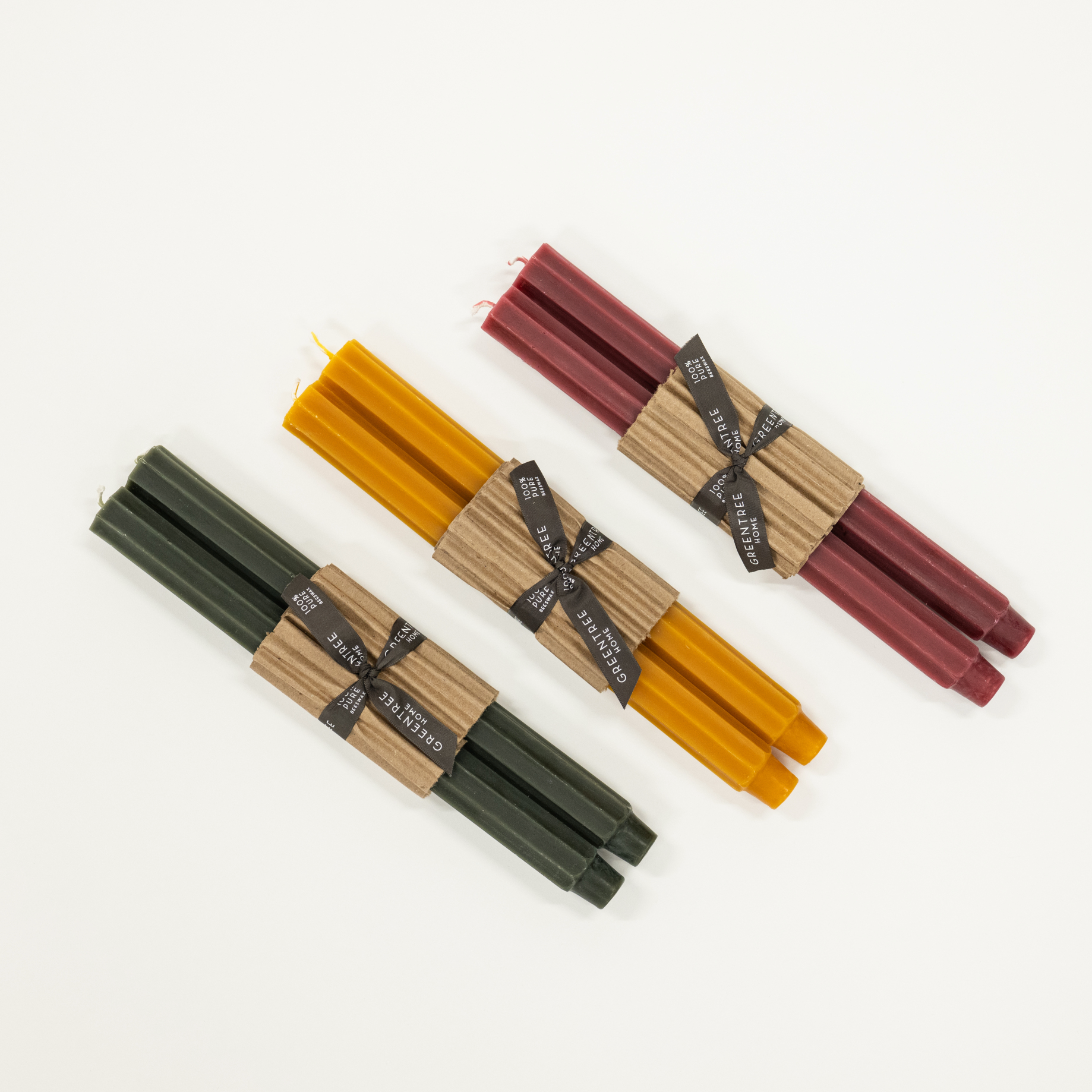 Set of three candles in different colors (green, yellow, deep pink) on a white background