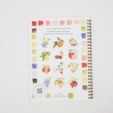 A spiral-bound watercolor painting notebook on a white background, featuring various watercolor fruit illustrations and color swatches on the cover.