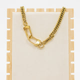 Gold chain necklace on a wooden stand with a white background
