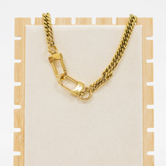 Gold chain necklace on a wooden stand with a white background