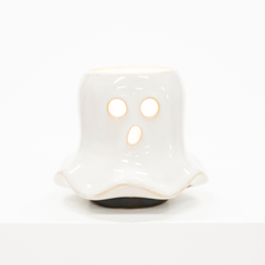 A small white ghost-shaped ceramic candle holder with cutout eyes and mouth, shown on a clean white background.