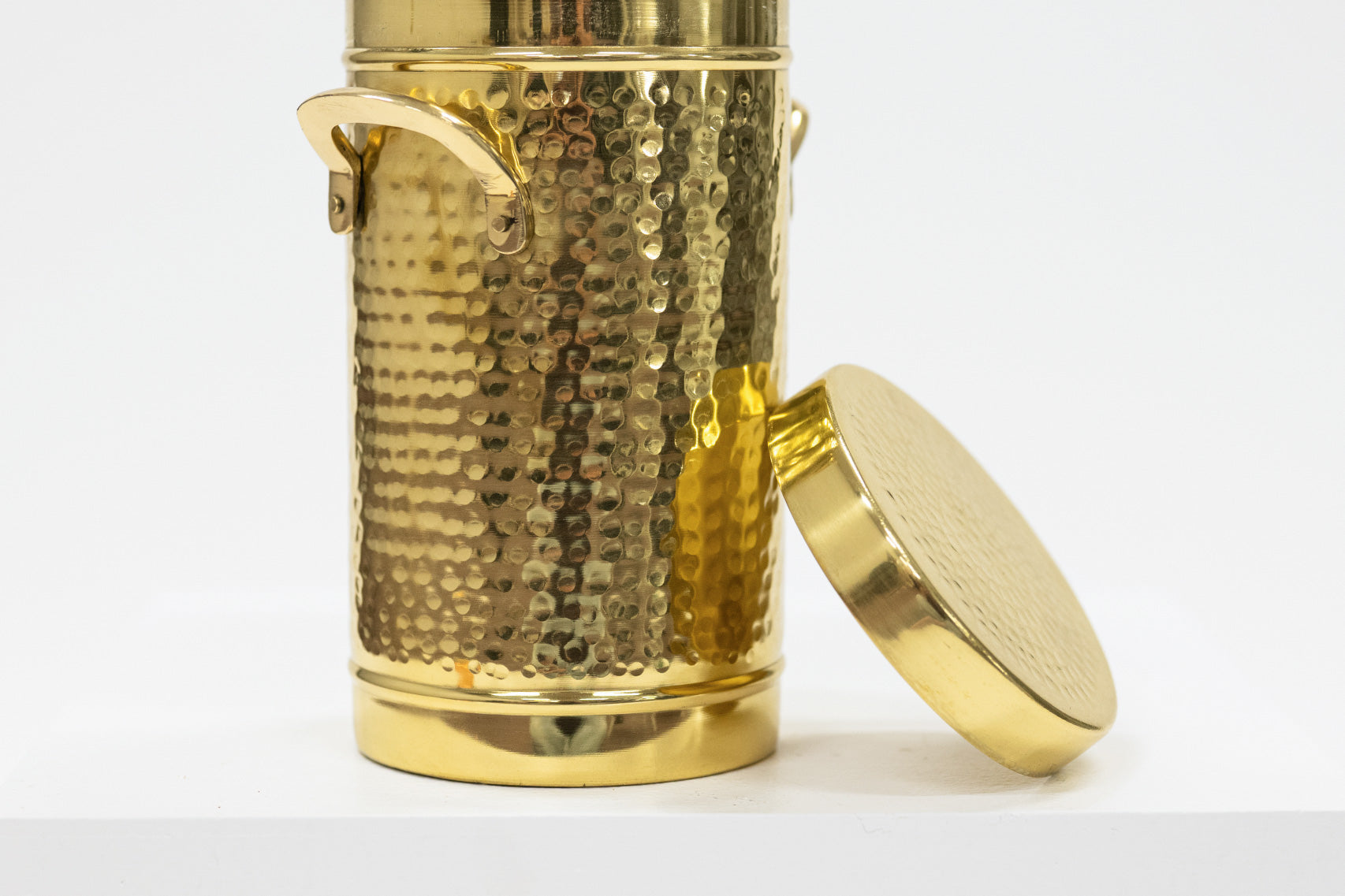 Gold metal container with textured surface and lid on a white background
