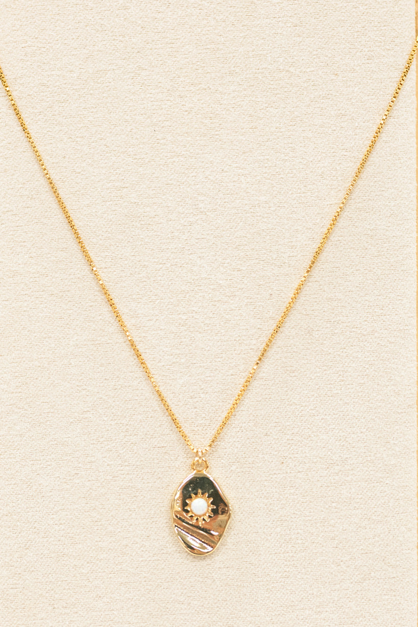 gold necklace featuring a pendant and small white opal. with a gold chain necklace