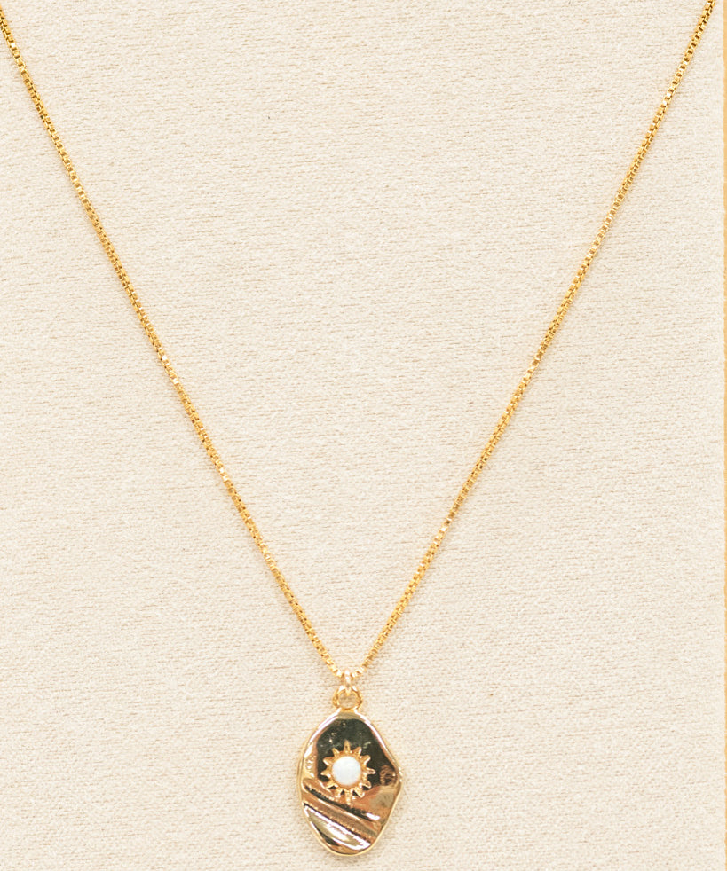 gold necklace featuring a pendant and small white opal. with a gold chain necklace