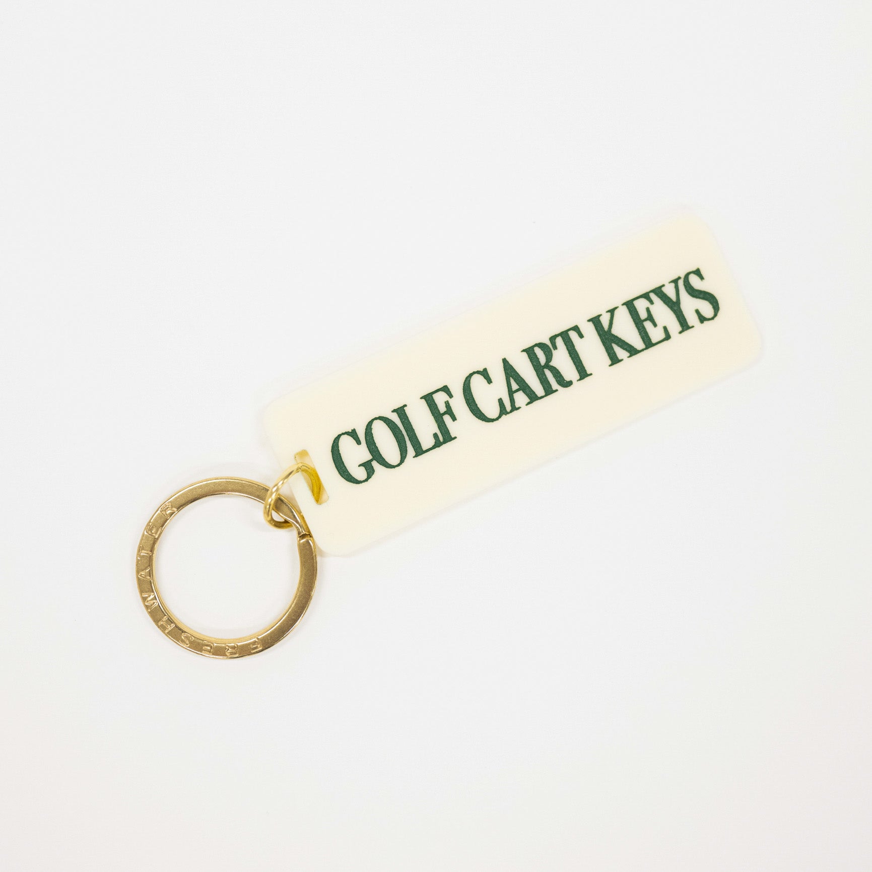A golf cart keys keychain with a cream-colored rectangular tag featuring green text and a gold split key ring, shown on a plain white background.