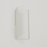Grid-patterned sticky note with text on a white background
