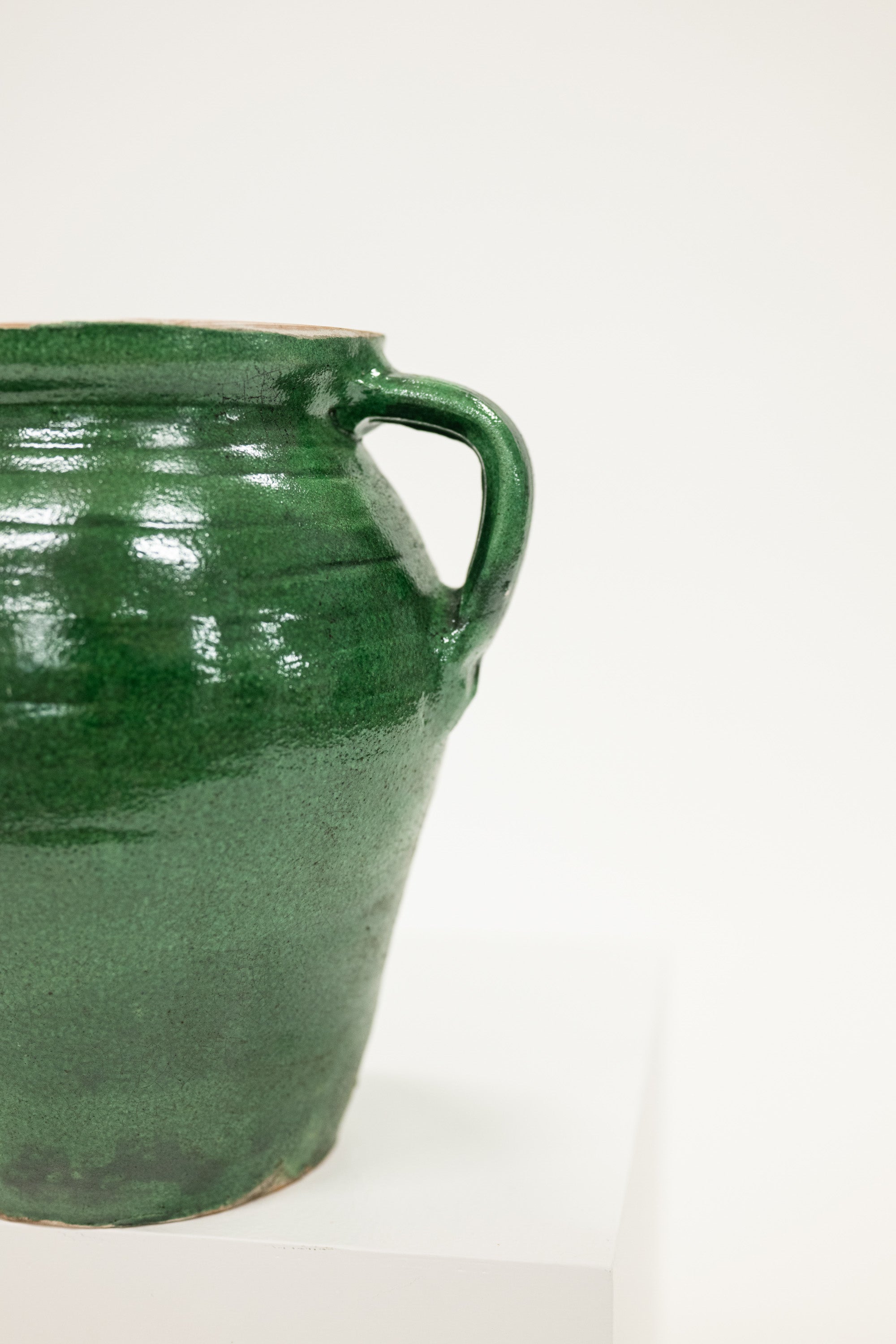 Green ceramic jar with a handle on a white background