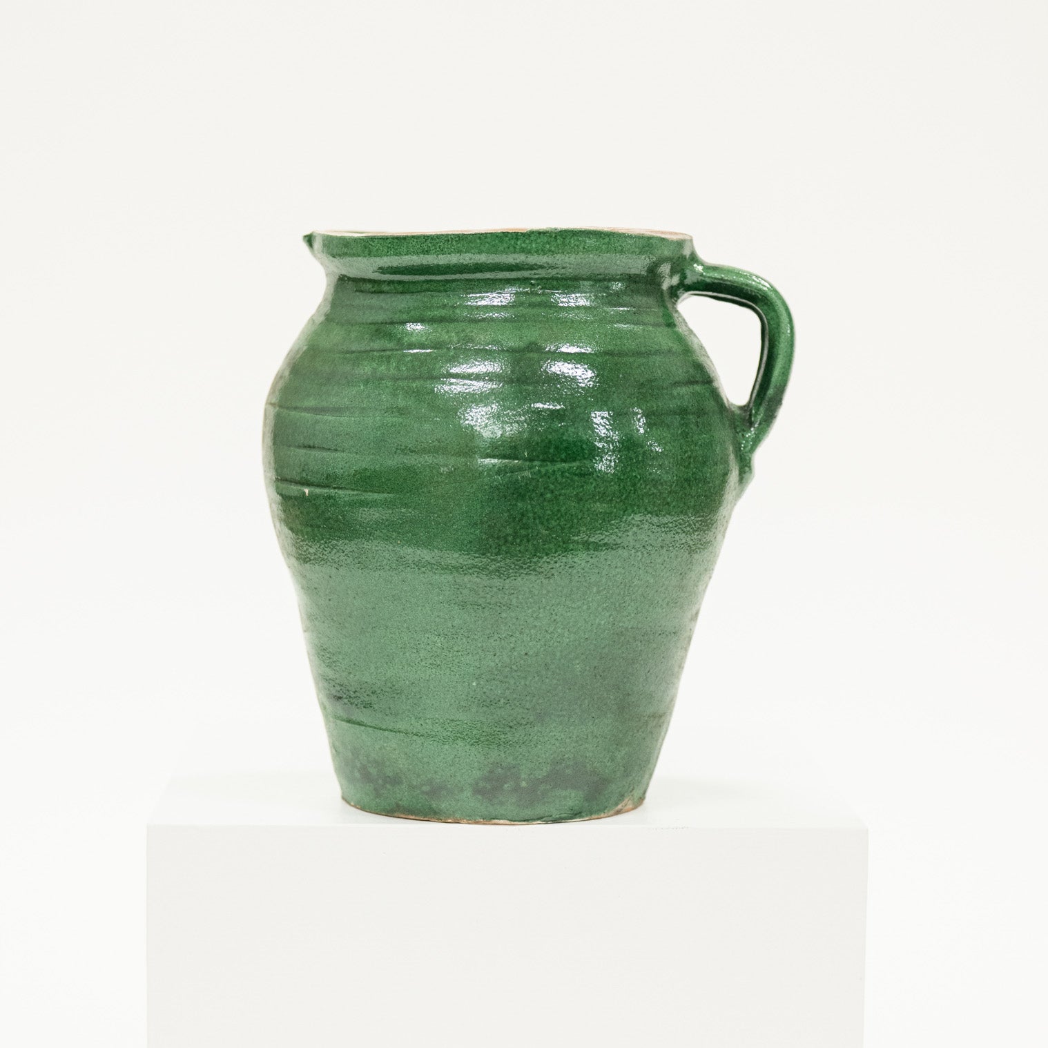 Green ceramic jar with a handle on a white background