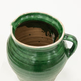 Green ceramic pitcher with a handle on a white background