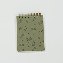 Small green notebook with floral patterns on a white background
