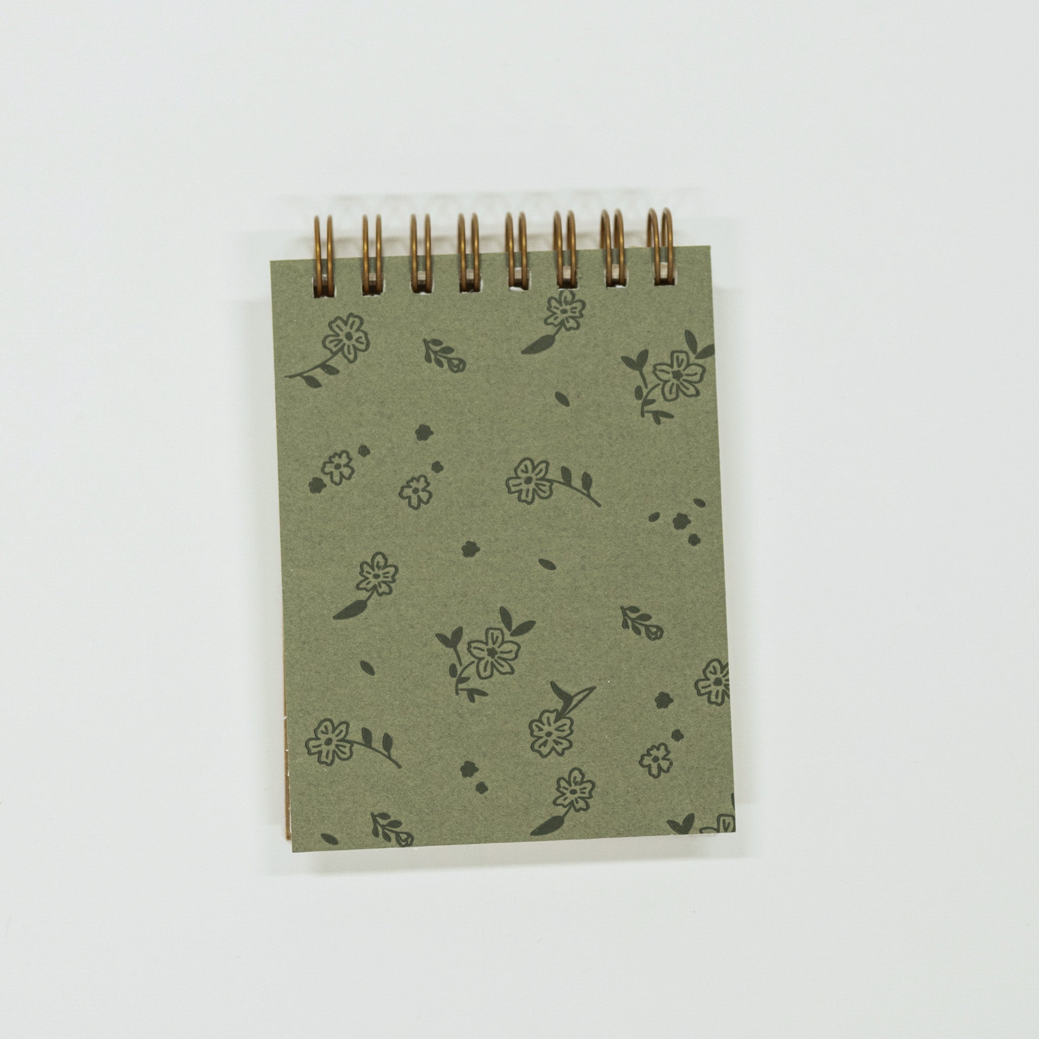 Small green notebook with floral patterns on a white background