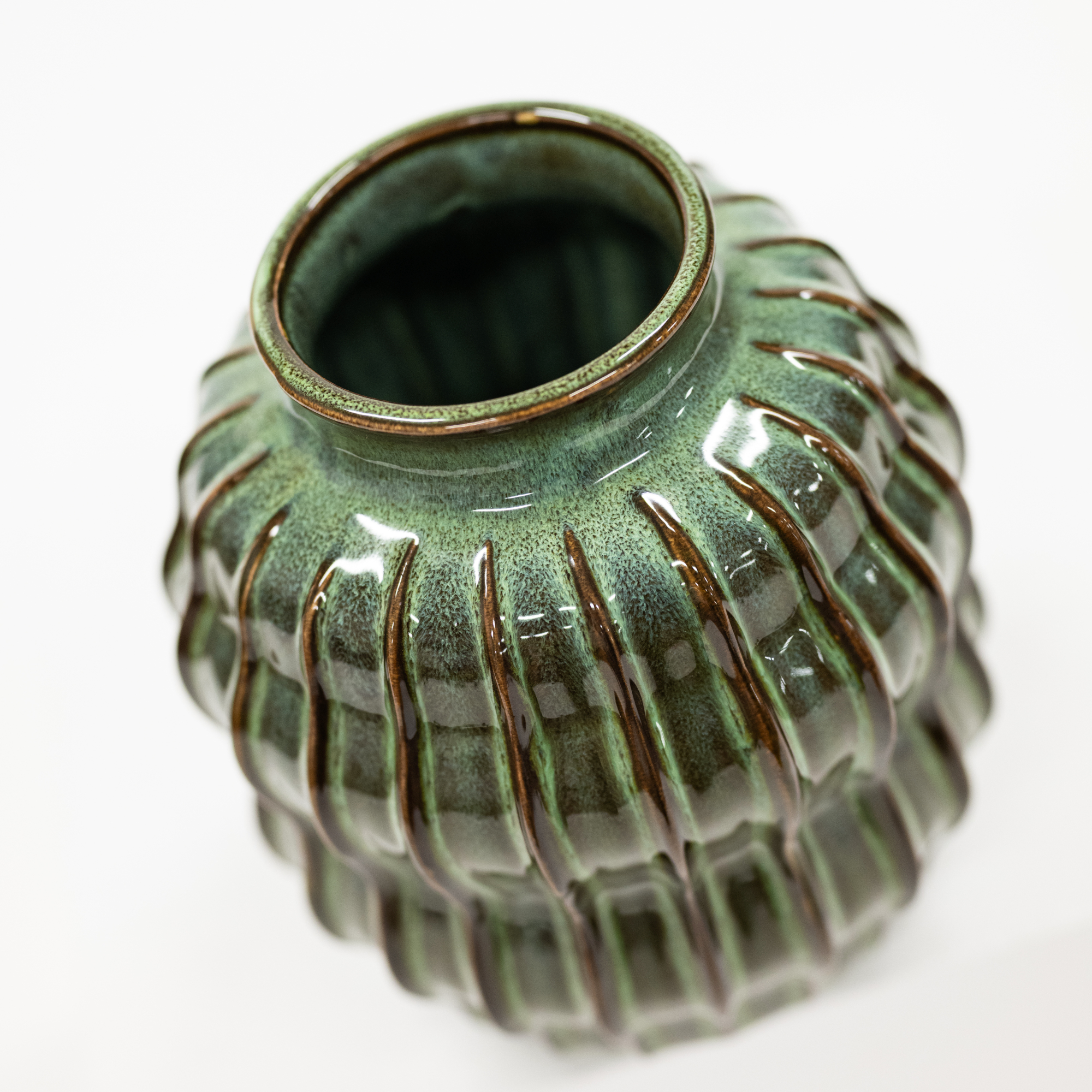 A small ribbed ceramic vase with a glossy green glaze and dark brown edging, shown on a plain white background.