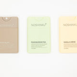 Three NOSHINKU refillable hand sanitizers on a white background: Santal Blanc in beige, Pear Blossom Tea in pale green, and Vanilla Crème in pale yellow.
