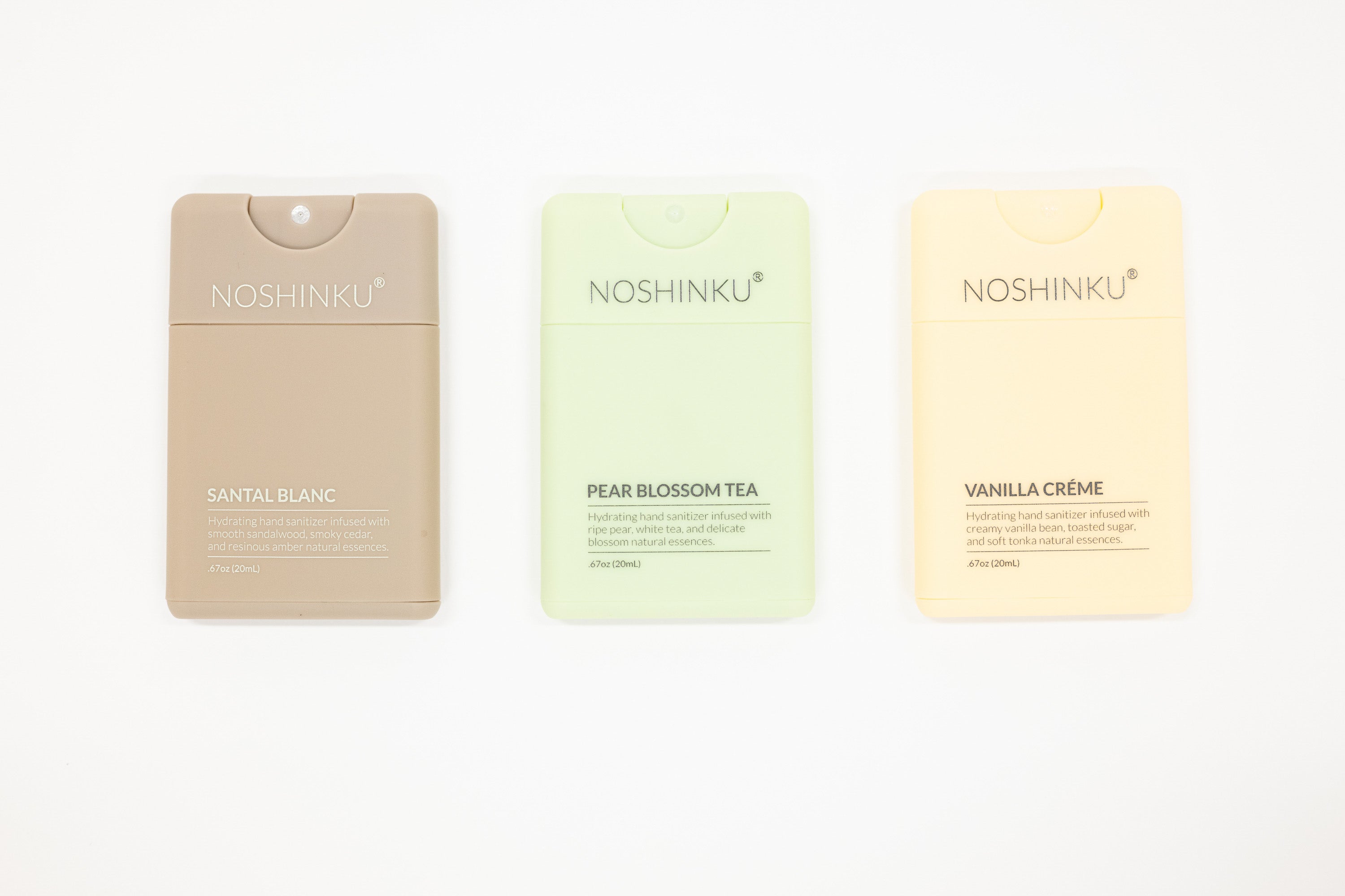Three NOSHINKU refillable hand sanitizers on a white background: Santal Blanc in beige, Pear Blossom Tea in pale green, and Vanilla Crème in pale yellow.