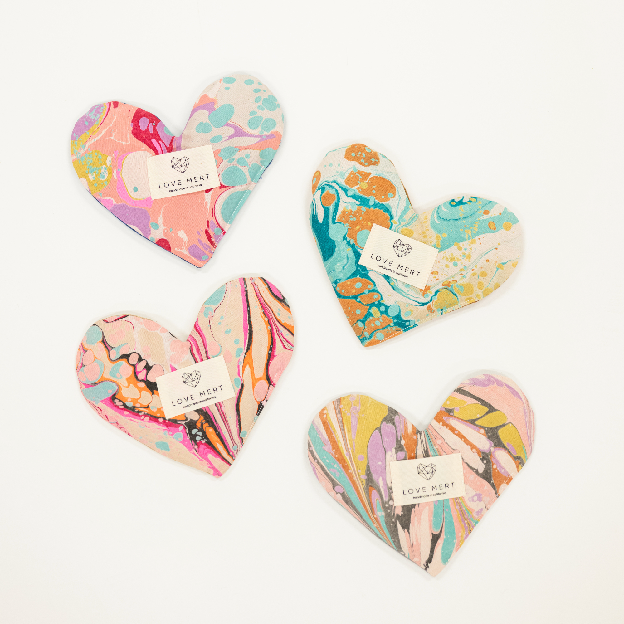 Four colorful heart-shaped products with 'Love Merit' tags on a white background