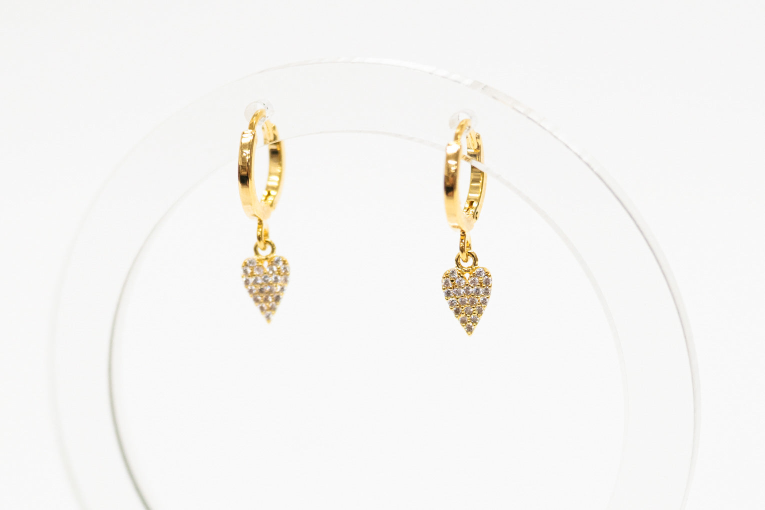 Gold hoop earrings with heart-shaped charms on a white background