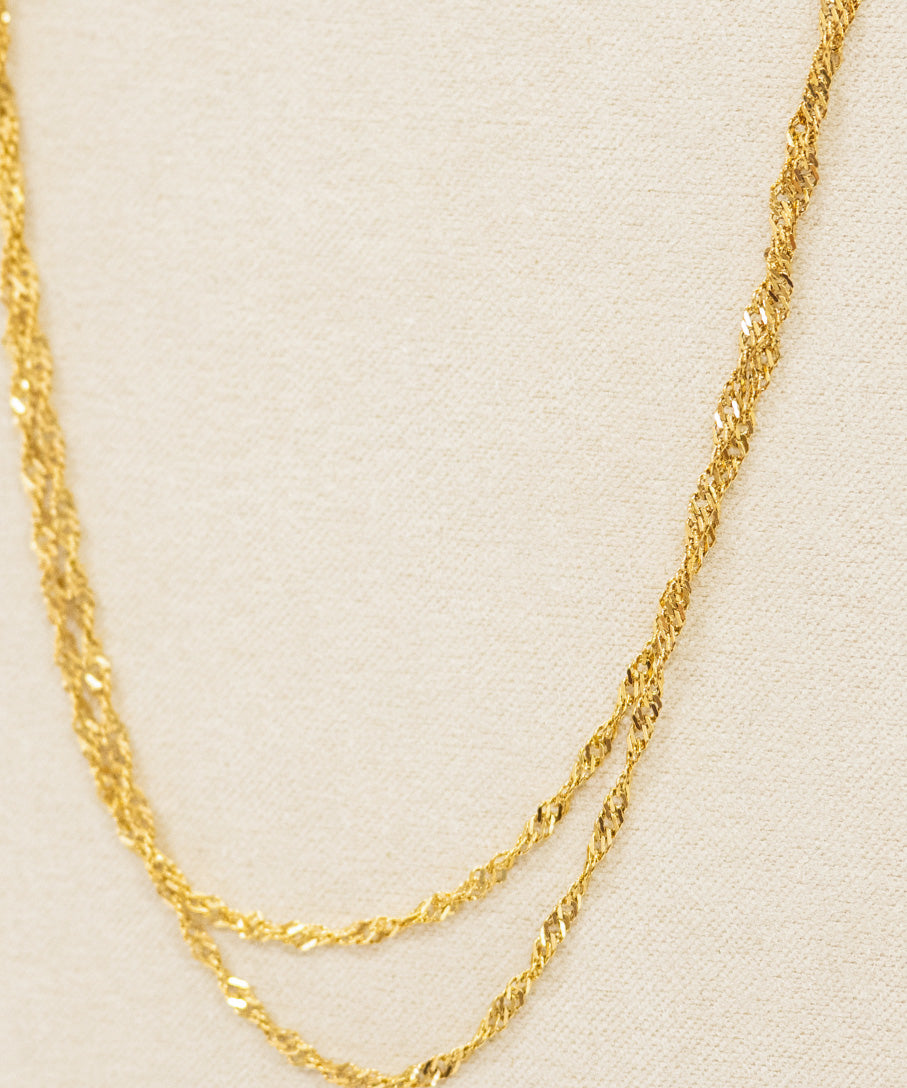 Gold chain necklace on a beige background