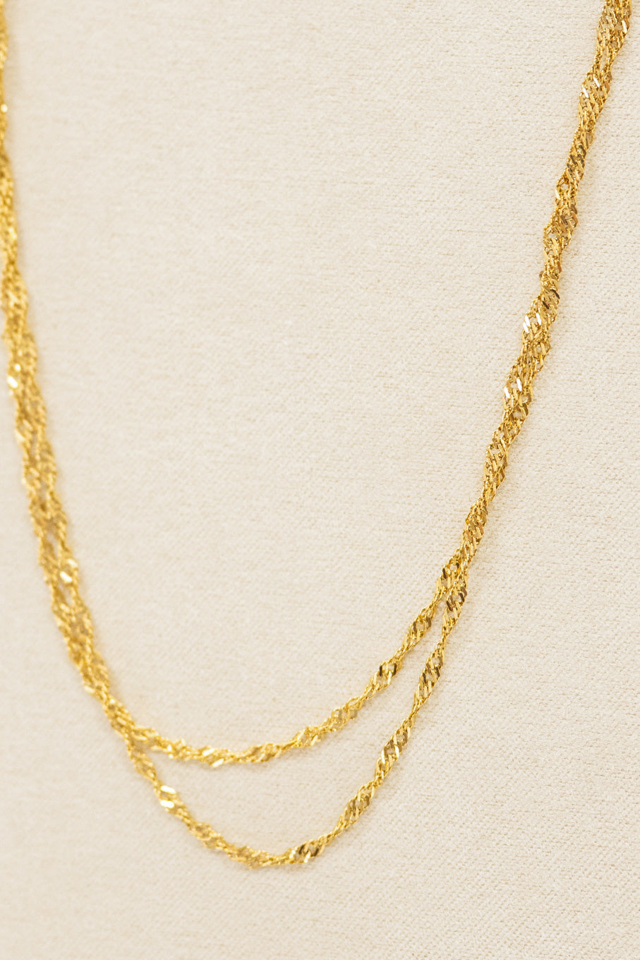 Gold chain necklace on a beige background