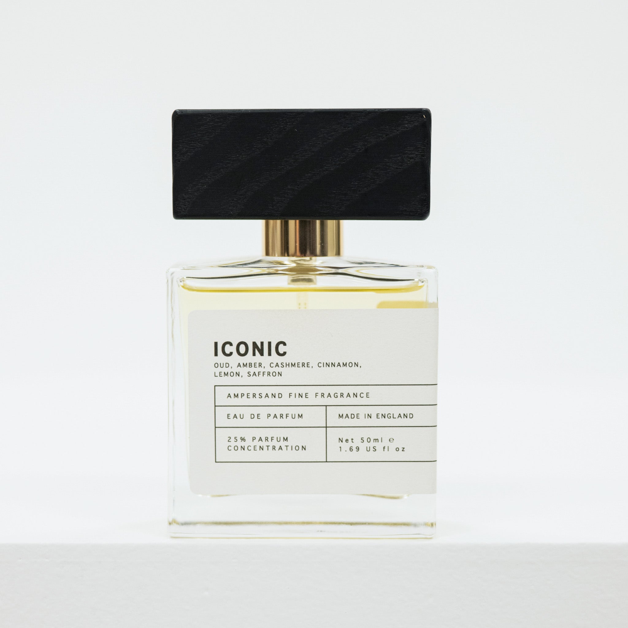 Perfume bottle with black cap and white label on a light gray background