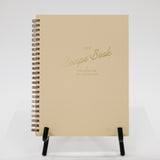 Beige recipe book with gold text on a white background