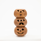 Three small carved jack-o'-lantern pumpkins stacked vertically, made of textured brown material with cutout facial features, on a plain white background.