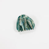 A single hair claw clip made of marbled green, blue, and white resin, photographed on a clean white background.