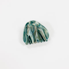 A single hair claw clip made of marbled green, blue, and white resin, photographed on a clean white background.