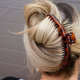 Close-up of a bun with a tortoiseshell hair clip against a neutral background