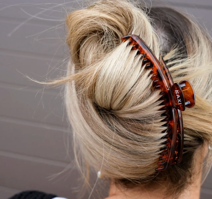 Close-up of a bun with a tortoiseshell hair clip against a neutral background