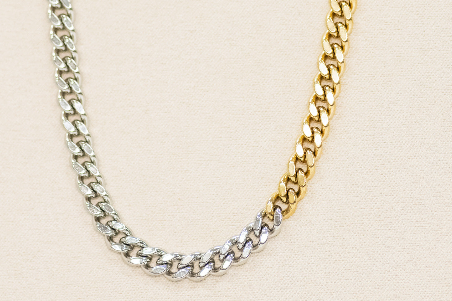 Two-tone gold and silver chain necklace on a beige background