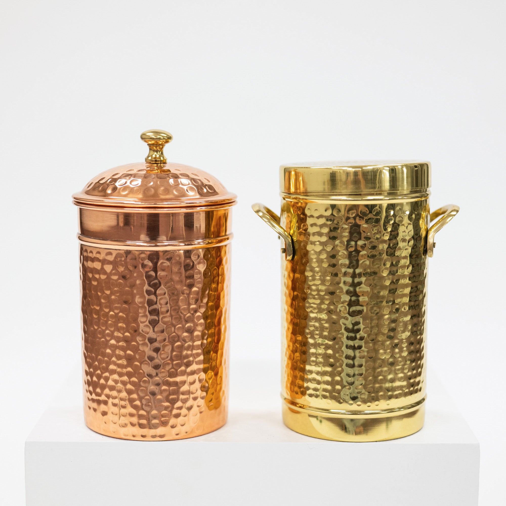 Two hammered metal containers, one copper and one gold, on a white background.