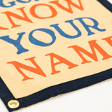 Colorful sign with text 'The world is going to know your name.' on a beige background.