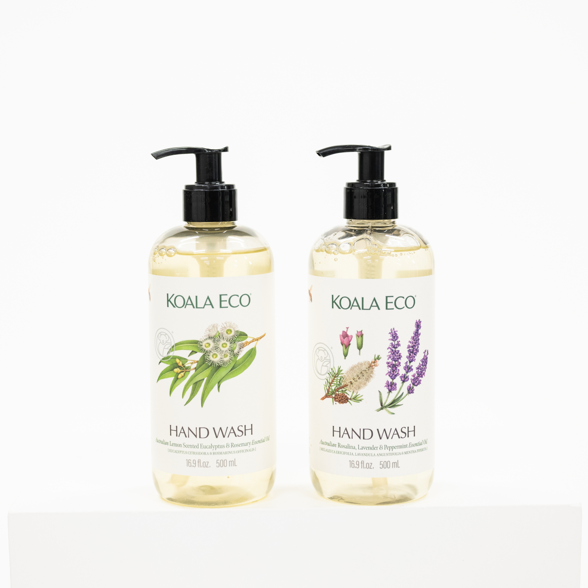 Two clear pump bottles of Koala Eco hand wash with black dispensers, standing side by side on a white surface against a white background. The left bottle features green eucalyptus illustrations, and the right bottle features purple lavender illustrations on white labels.