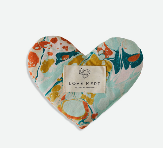 Heart-shaped eye pillow with marbled pattern and 'LOVE MERT' label on a white background