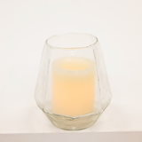 Clear glass candle holder with a lit candle on a white background