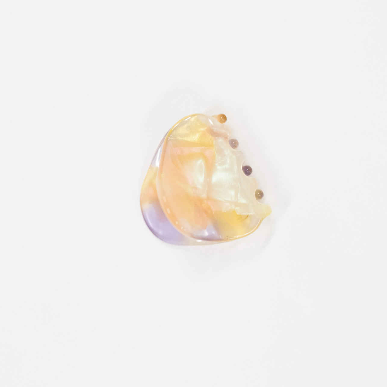 A single iridescent hair claw clip accessory with a pearlescent yellow, peach, and lavender sheen, photographed on a clean white background.