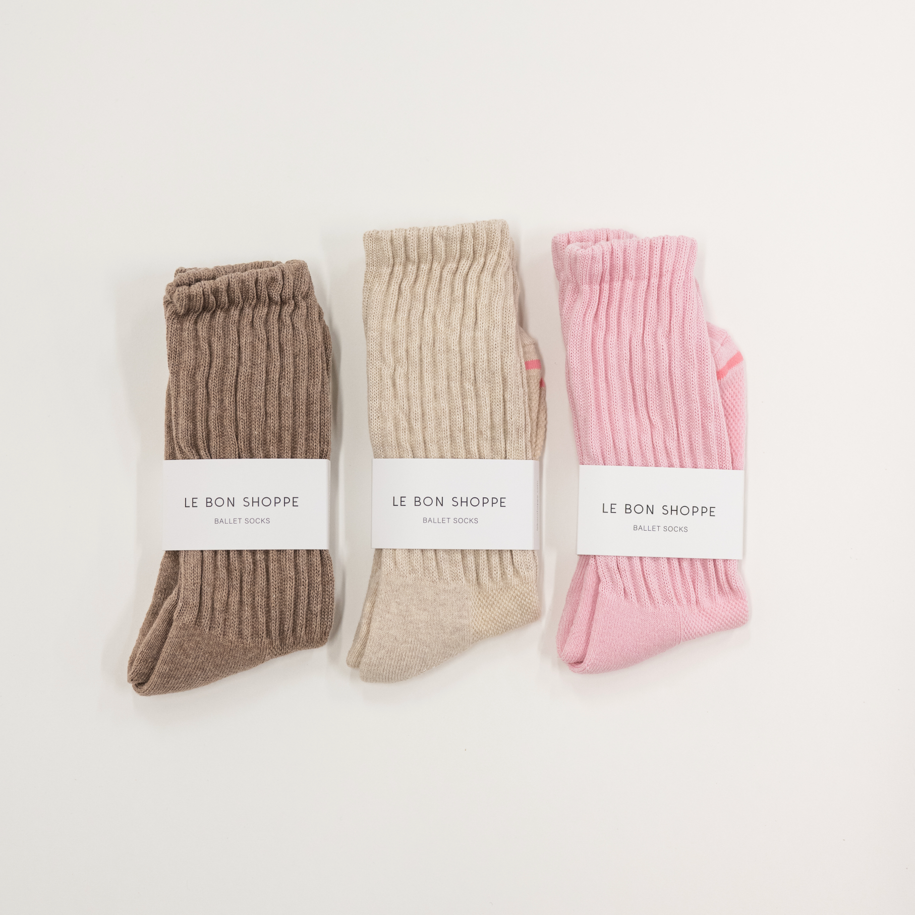 Three pairs of socks in brown, beige, and pink with 'Le Bon Shoppe' labels on a white background.