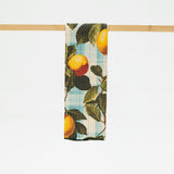 Towel with lemon and leaf pattern hanging on a wooden rod against a white background