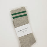 Gray sock with green stripes and a white label on a light beige background