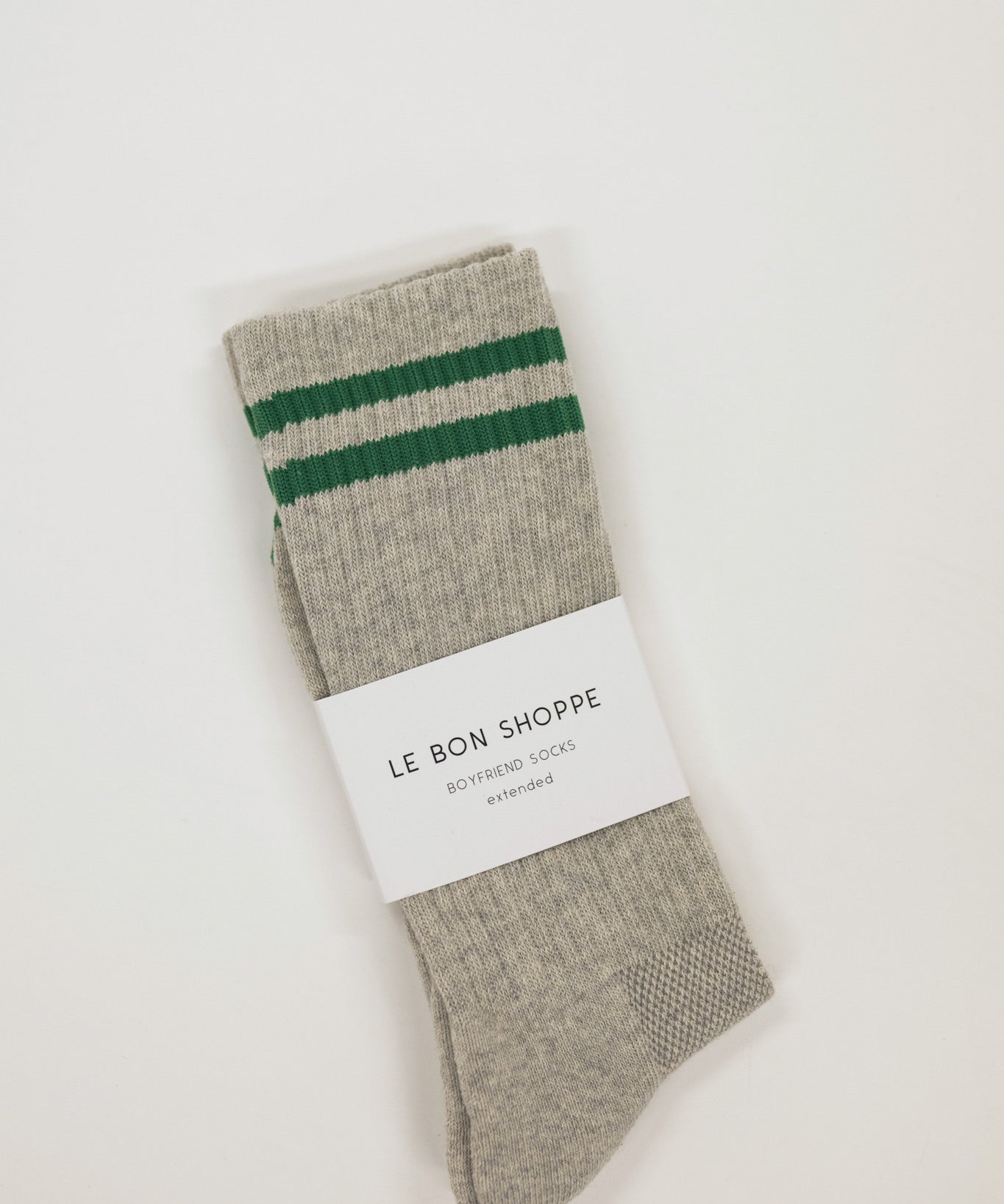 Gray sock with green stripes and a white label on a light beige background