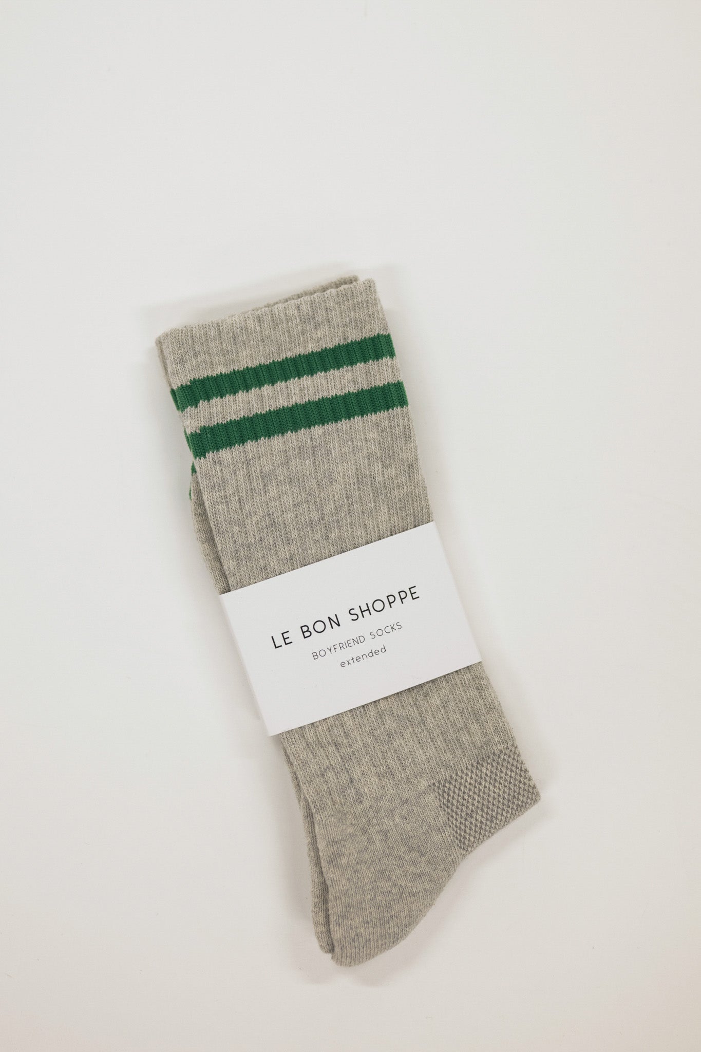 Gray sock with green stripes and a white label on a light beige background