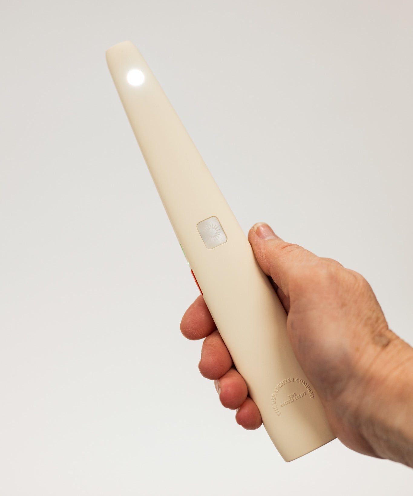 Hand holding a white usb lighter with a light on a plain background