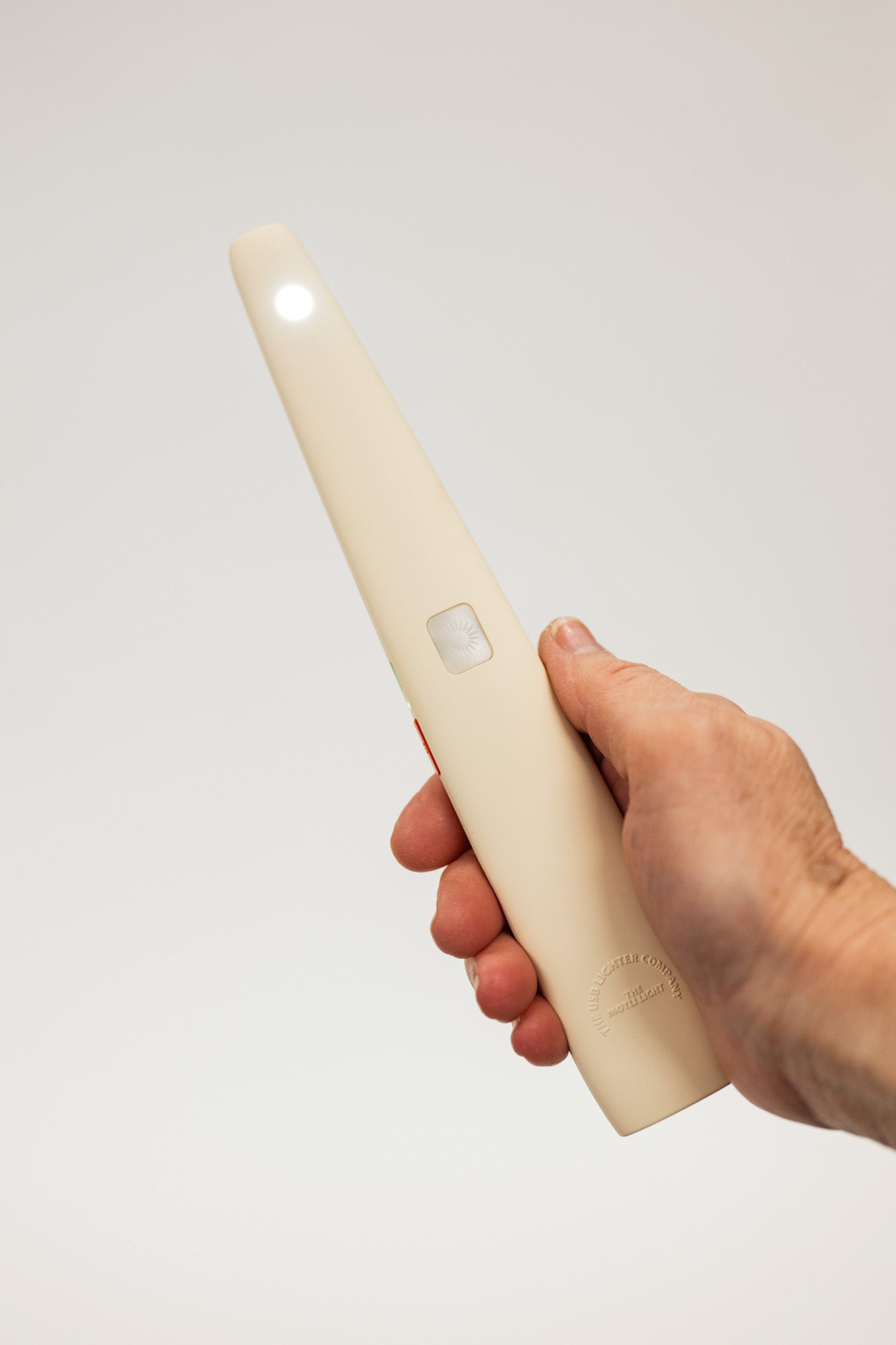 Hand holding a white usb lighter with a light on a plain background