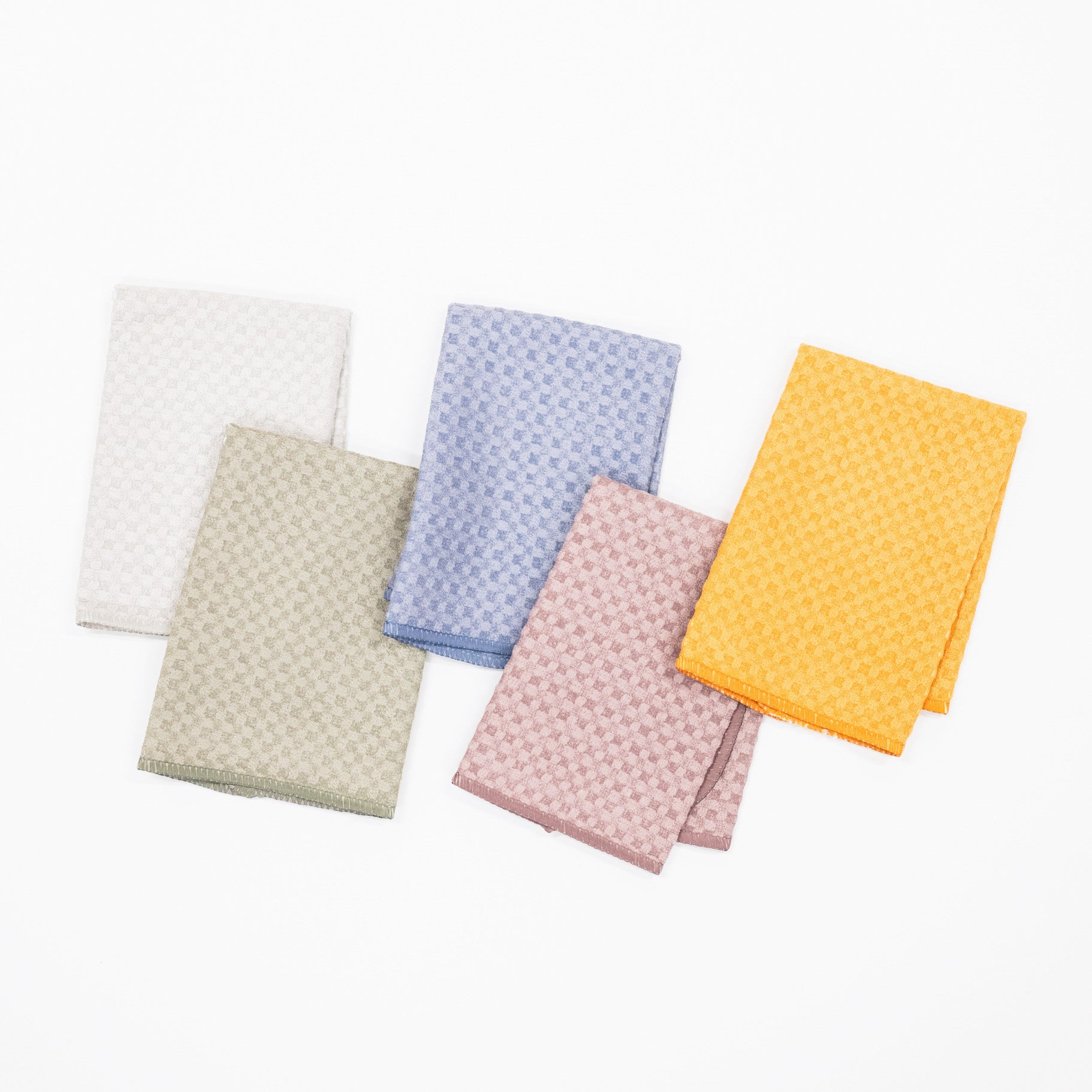 Five folded microfiber dishcloths in white, beige, light blue, pink, and mustard yellow arranged on a plain white background.