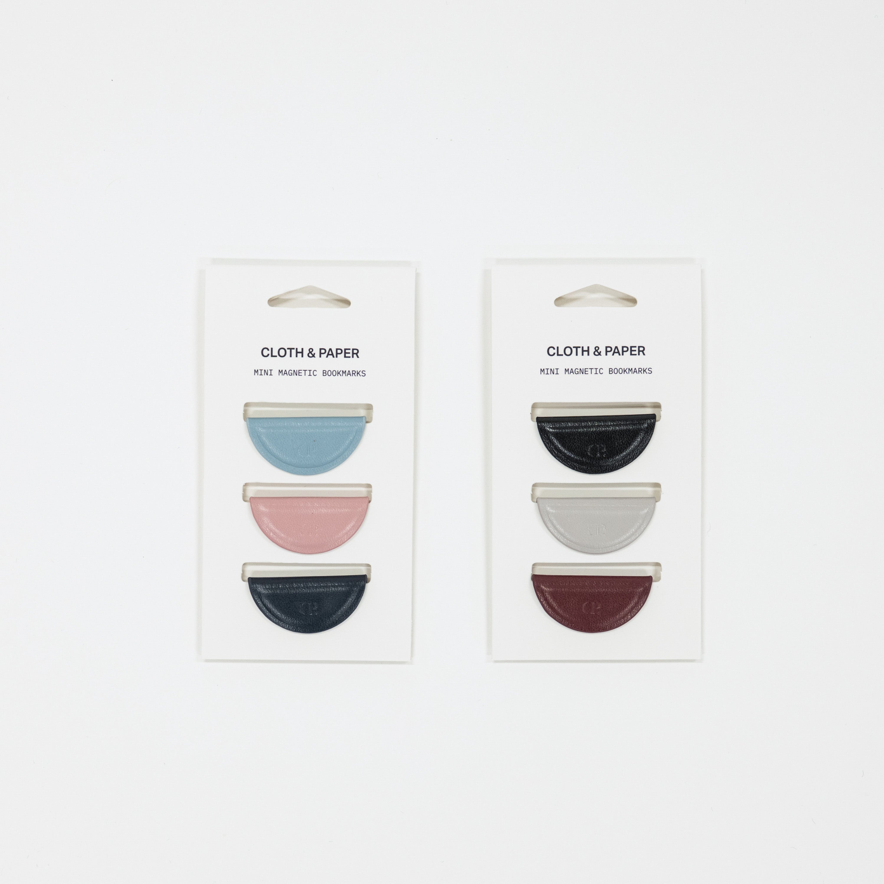 Two packages of 'Cloth & Paper' magnetic bookmarks with colorful designs on a white background.