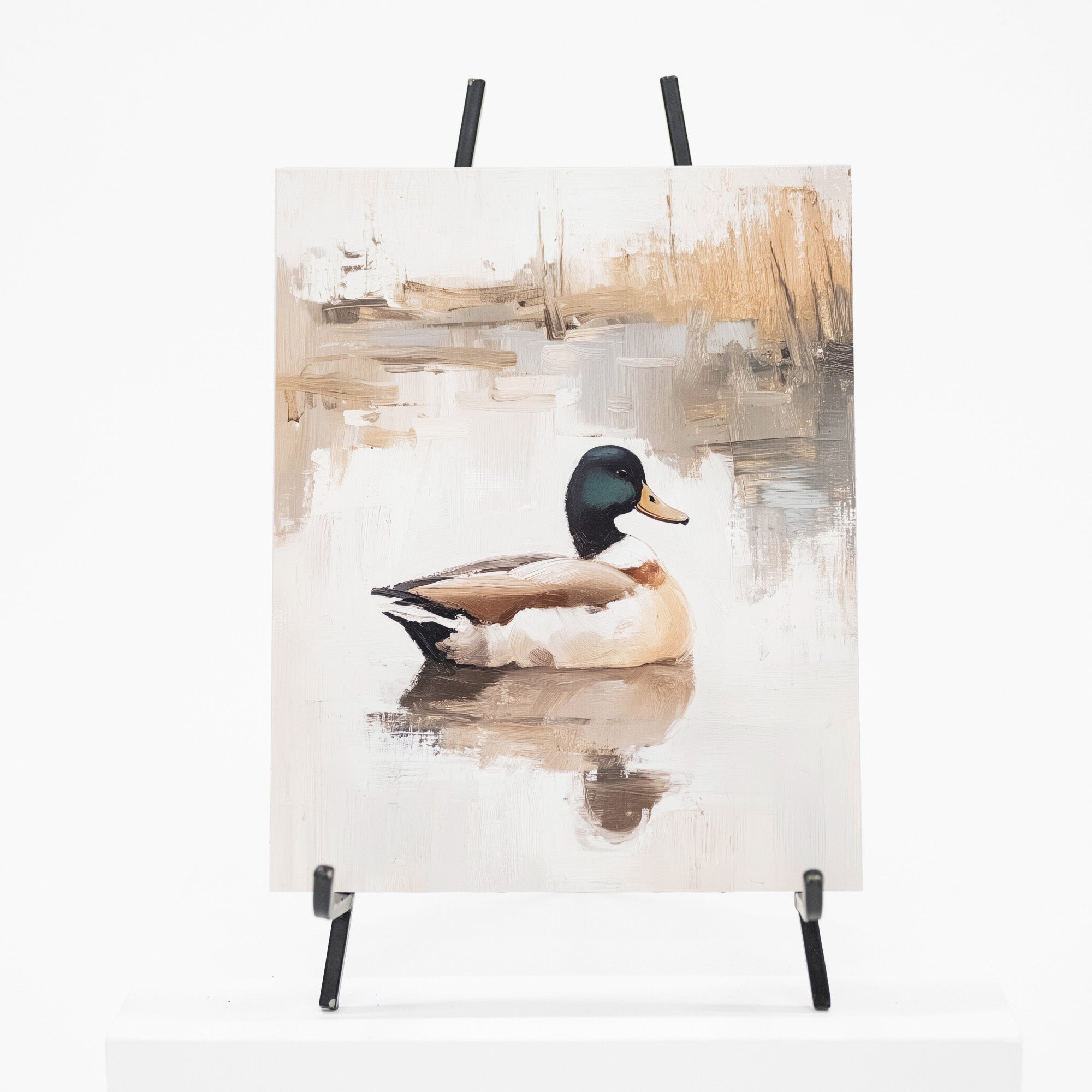 A vertical canvas painting of a mallard duck on a reflective pond, displayed on a black easel against a clean white background.