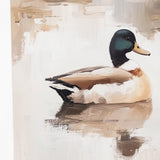 A canvas painting of a mallard duck floating on water, displayed on an easel. The painting features a detailed mallard with a dark green head, white chest, and brown body, set against a soft beige and white background with brushstroke textures.