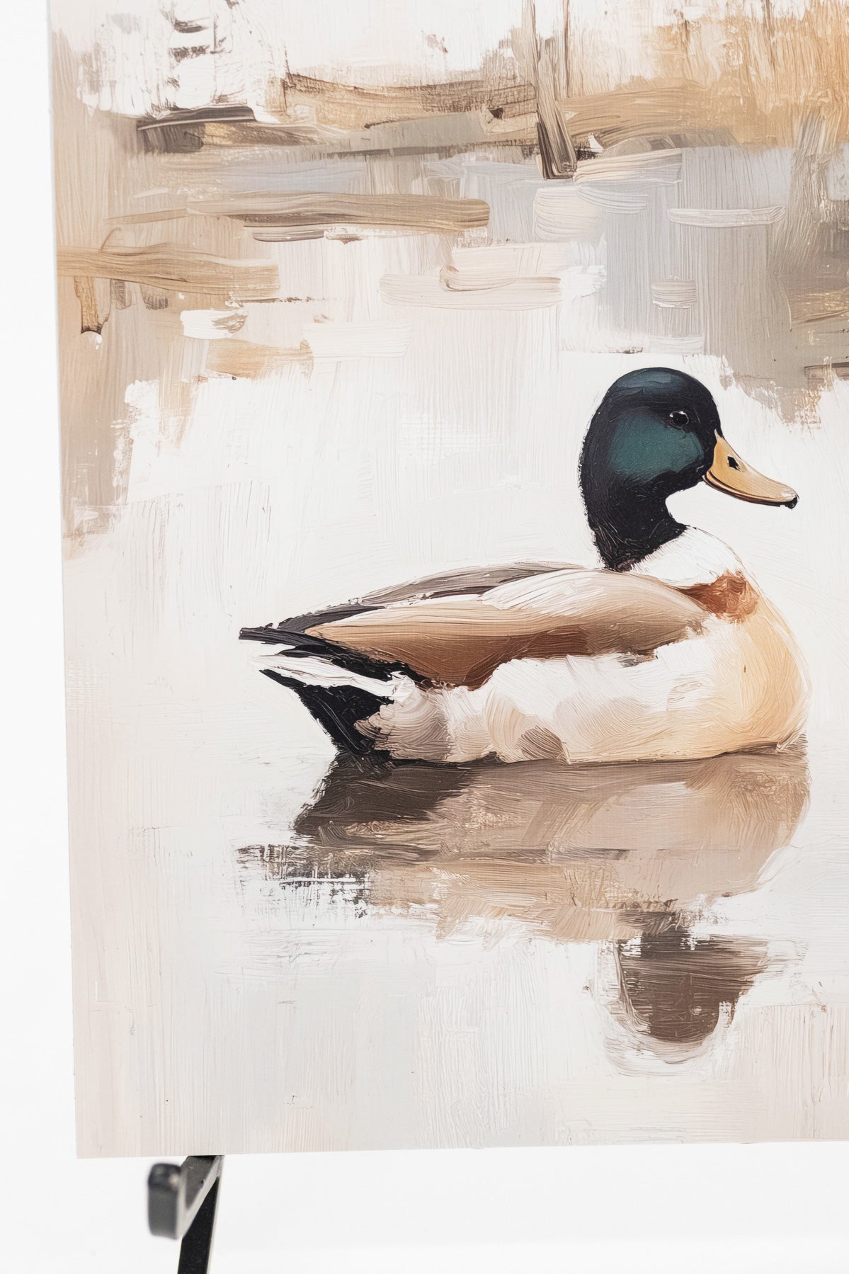 A canvas painting of a mallard duck floating on water, displayed on an easel. The painting features a detailed mallard with a dark green head, white chest, and brown body, set against a soft beige and white background with brushstroke textures.